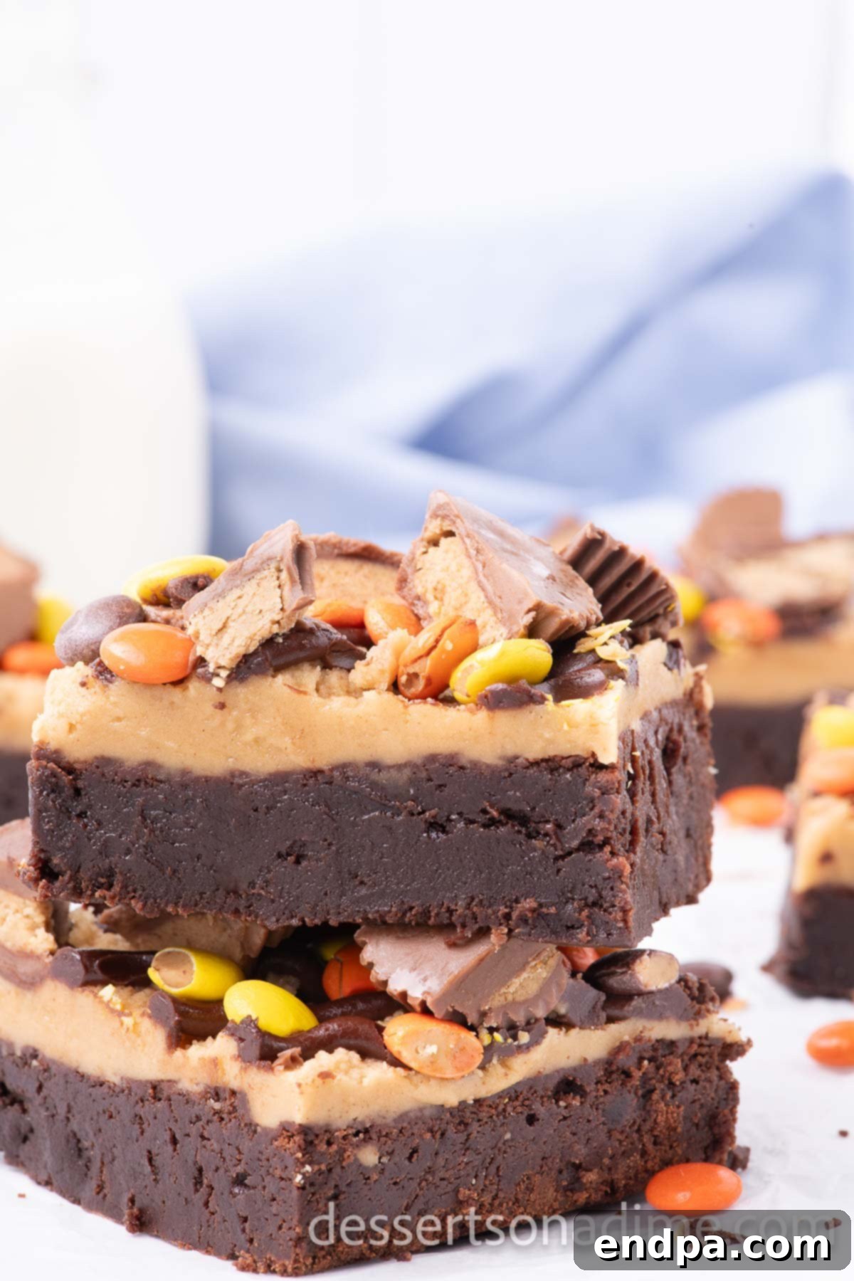 Decadent Reese's Peanut Butter Brownies 2 Stacked Chocolate Peanut Butter Brownies adorned with Reese's Pieces and a drizzle of chocolate.