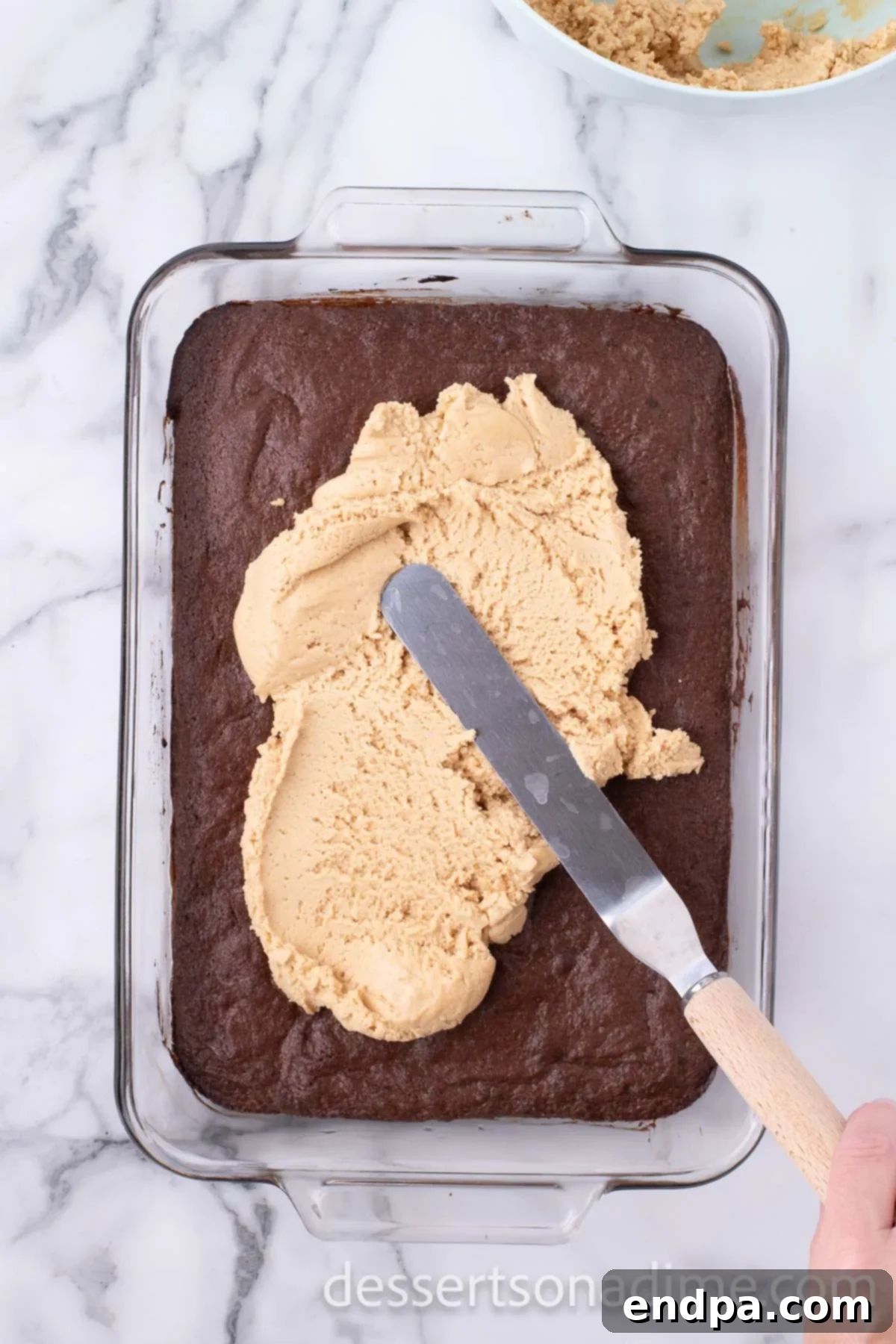 Decadent Reese's Peanut Butter Brownies 10 Peanut butter frosting being spread evenly on top of cooled brownies.