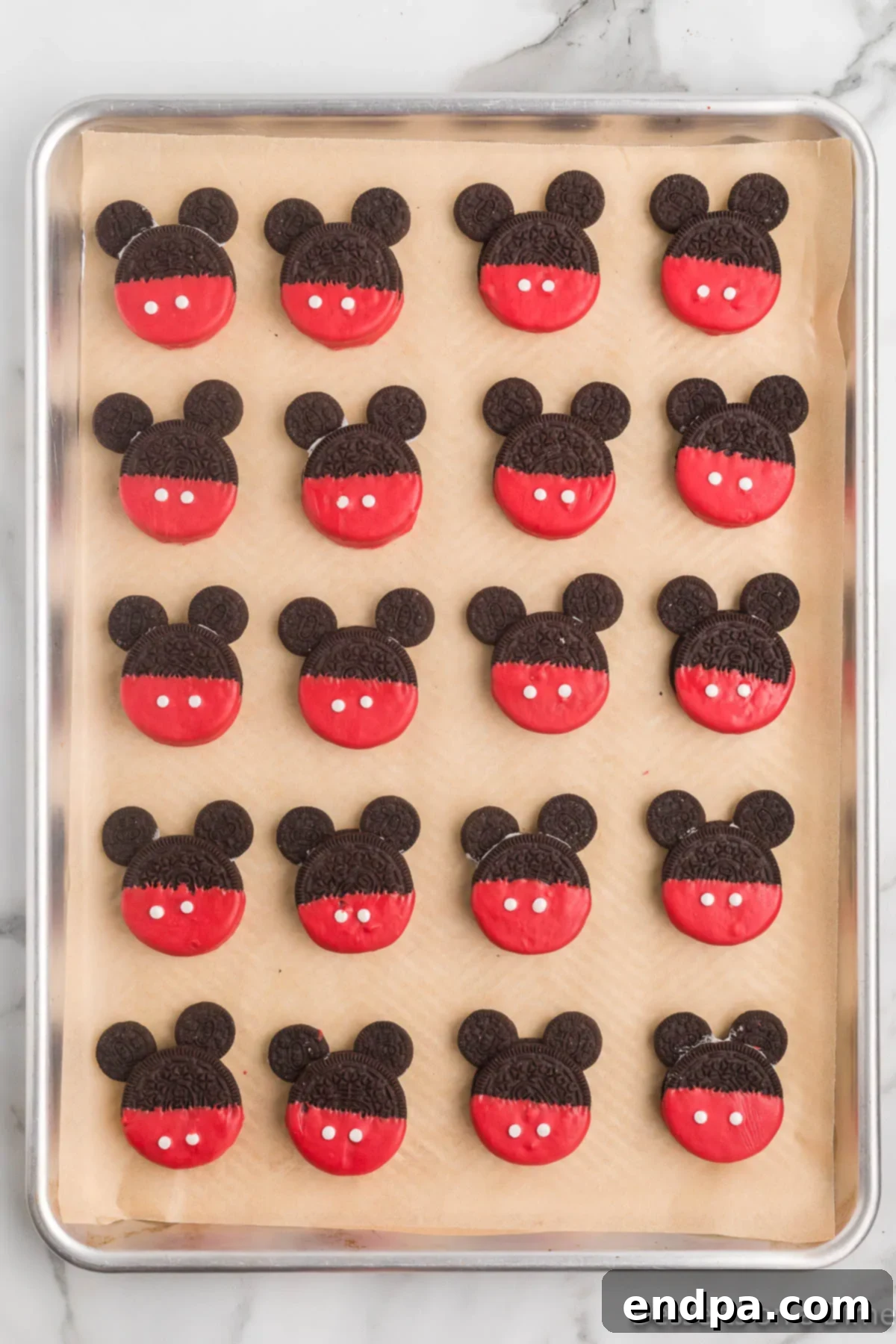 Mickey's Magical Oreo Treats 9 A collection of beautifully decorated Mickey Mouse Oreo cookies arranged on a baking sheet, allowing the candy melts to fully set and harden before serving.