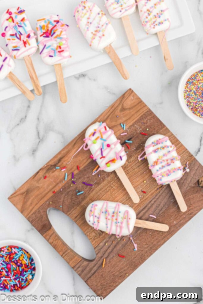 Dessert Pops 11 Decorated cakesicles on a wooden board, drizzled with colorful candy melts and topped with sprinkles.