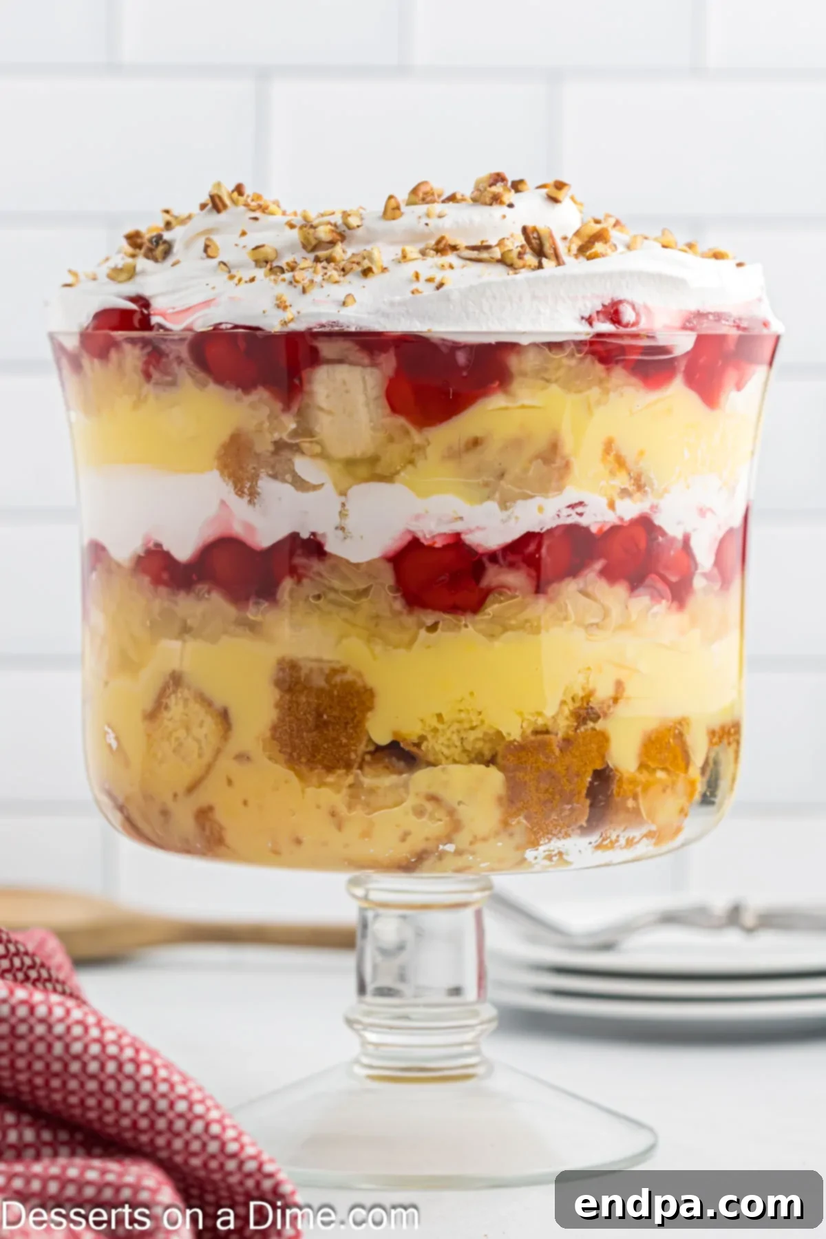 A beautifully layered Punch Bowl Cake in a clear trifle dish, showcasing its colorful components.