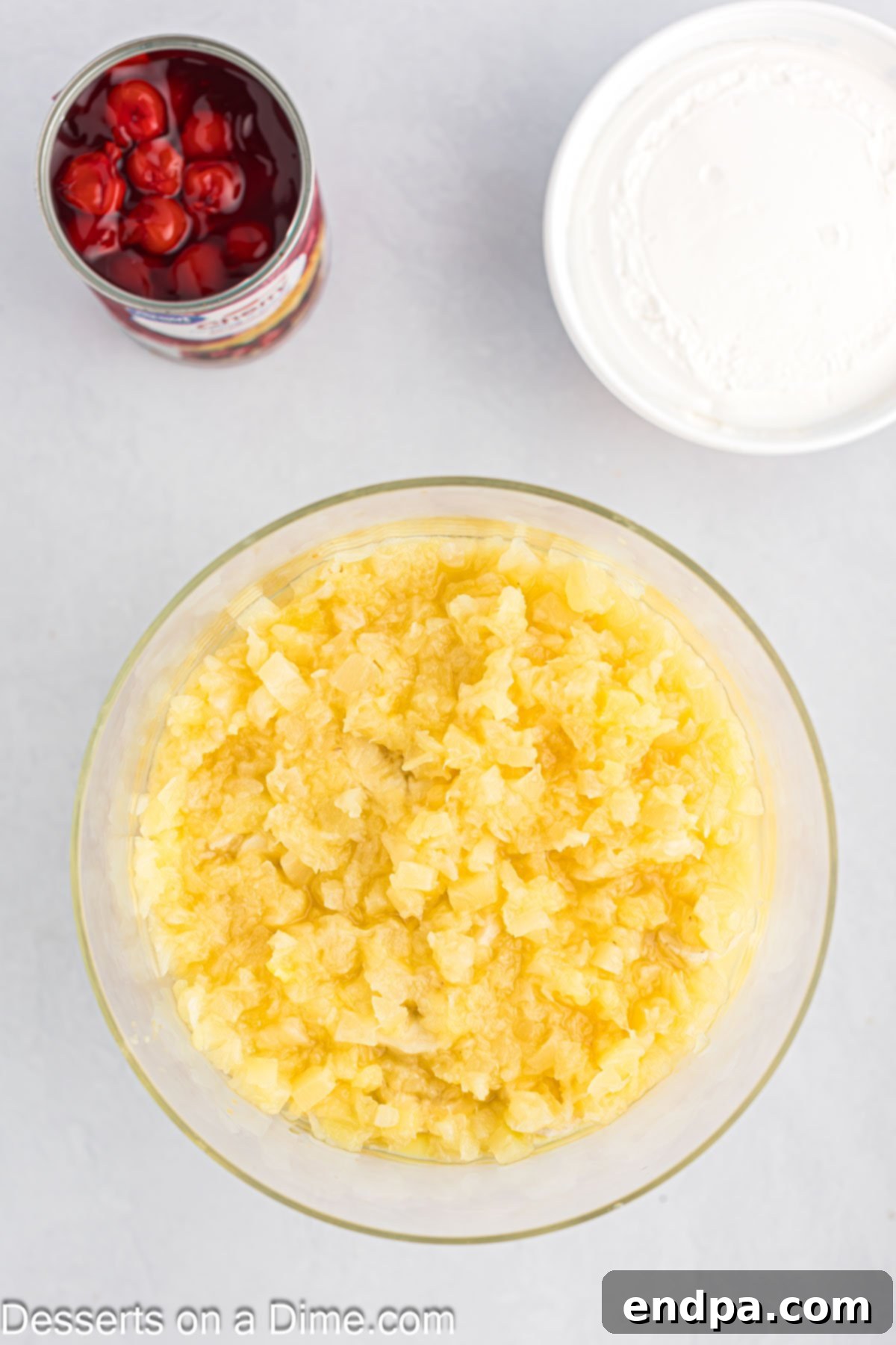 A layer of drained crushed pineapple evenly spread in a trifle dish as part of the Punch Bowl Cake assembly.
