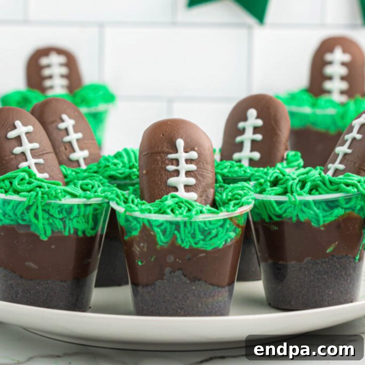Chocolate football dessert cups with green frosting for game day.