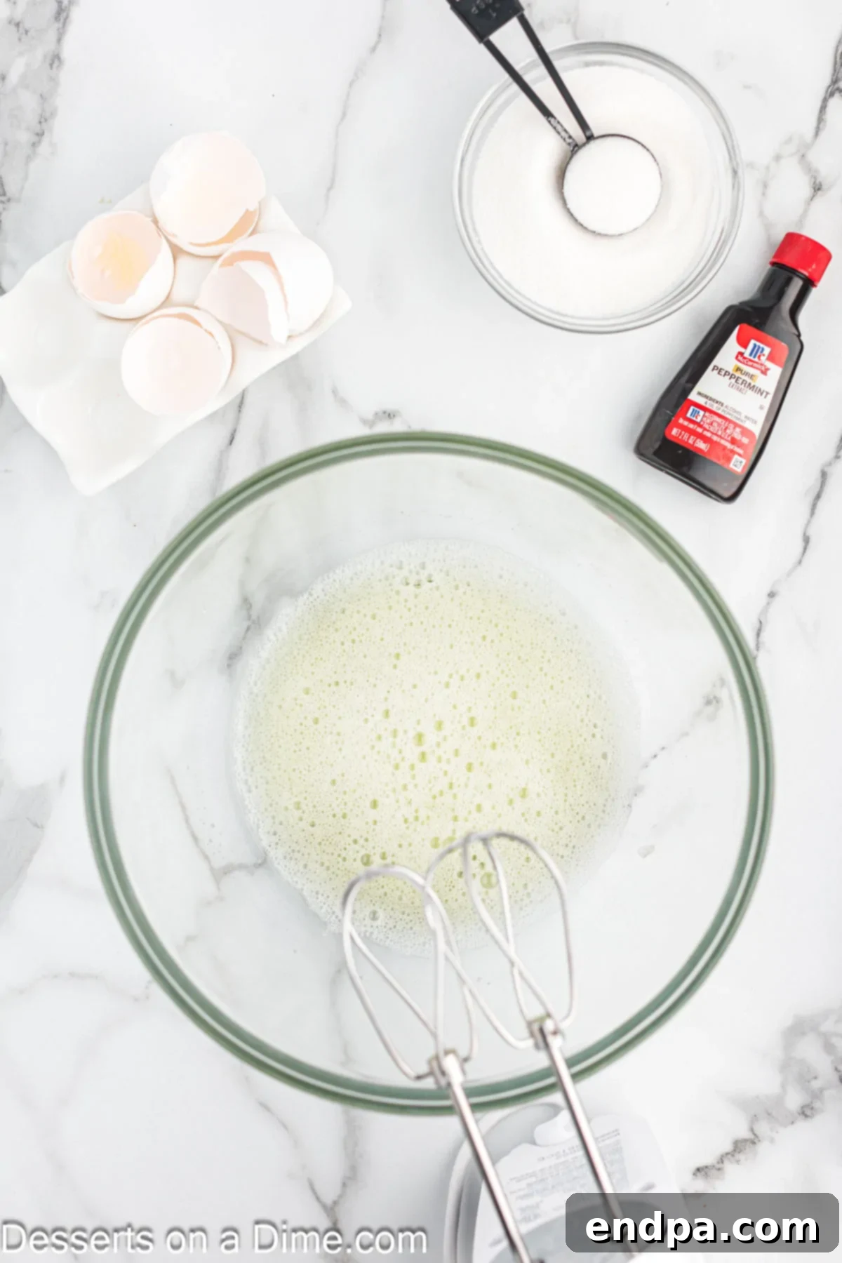 Peppermint Cloud Kisses 4 Mixing bowl with egg whites and cream of tartar being beaten to frothy consistency.