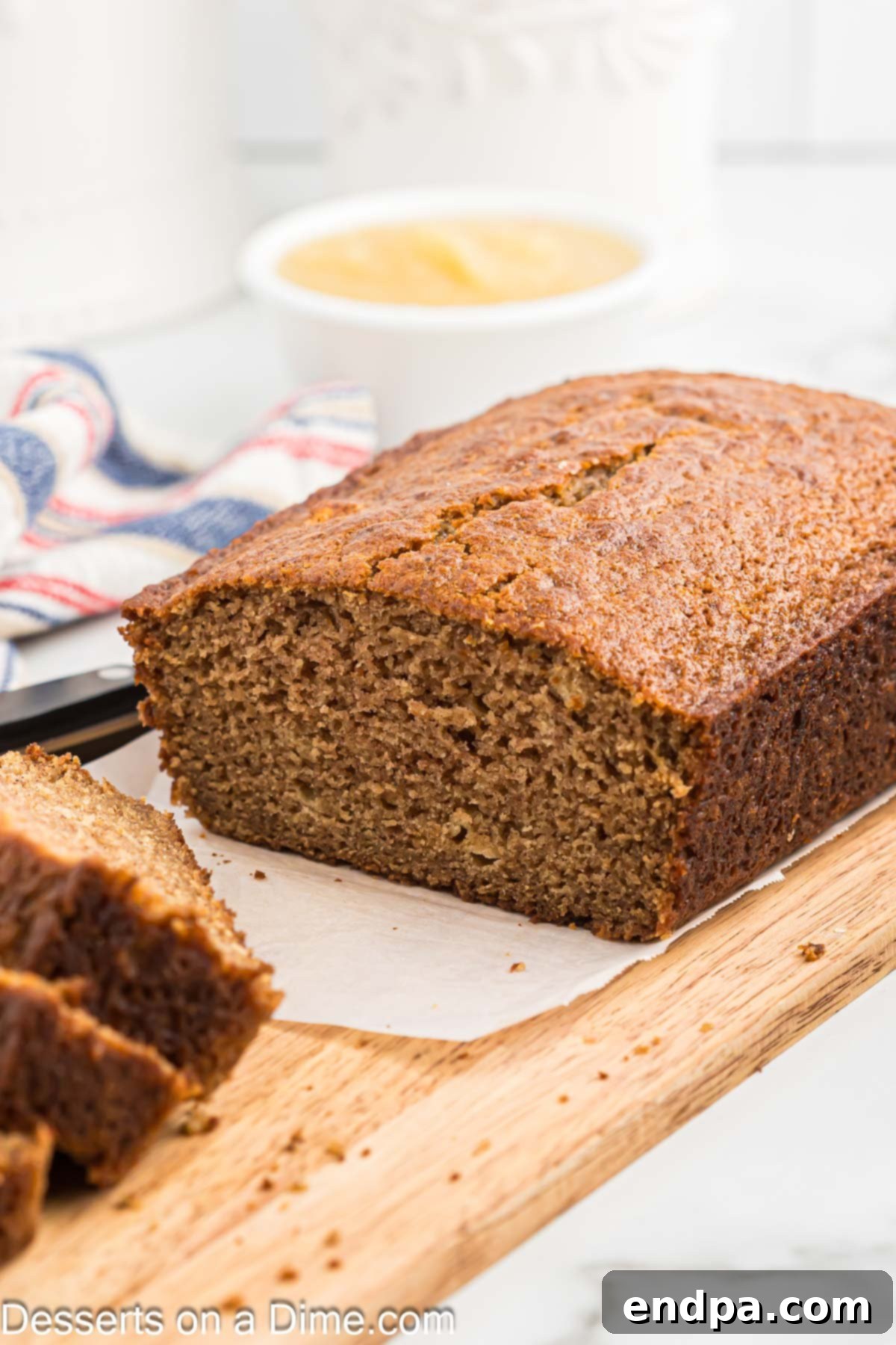 Applesauce bread on a cutting board being sliced.