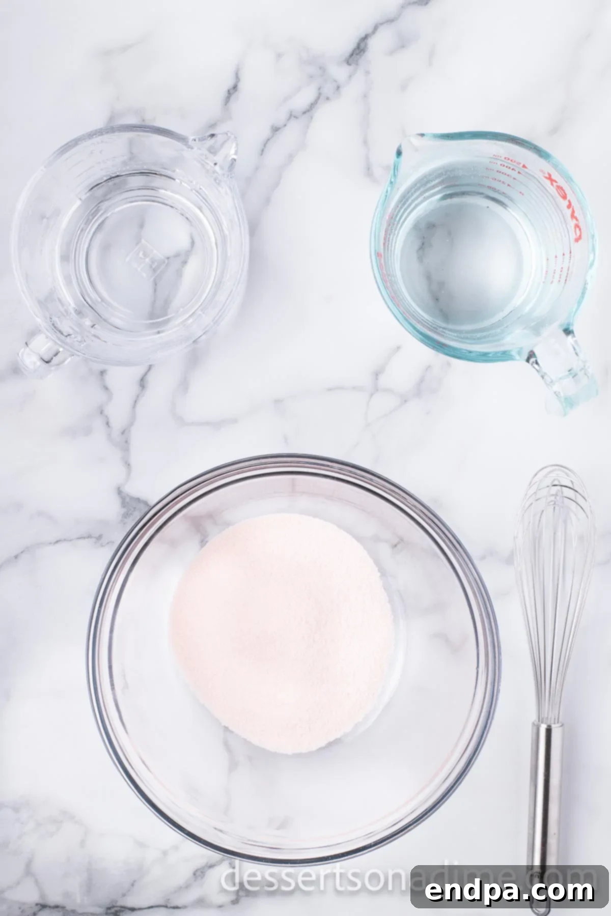 Large mixing bowl with orange Jell-O powder being combined with boiling water, a whisk visible in the mixture.
