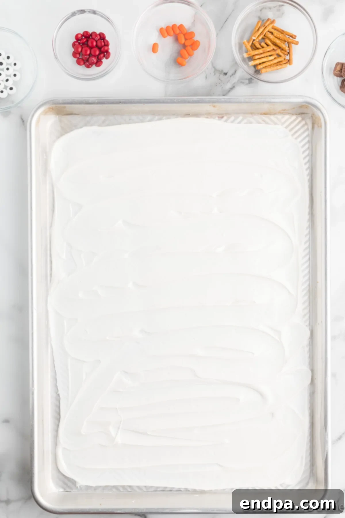 Frosty Meltdown Bark 5 Melted chocolate spread evenly on a baking sheet, forming a smooth base.