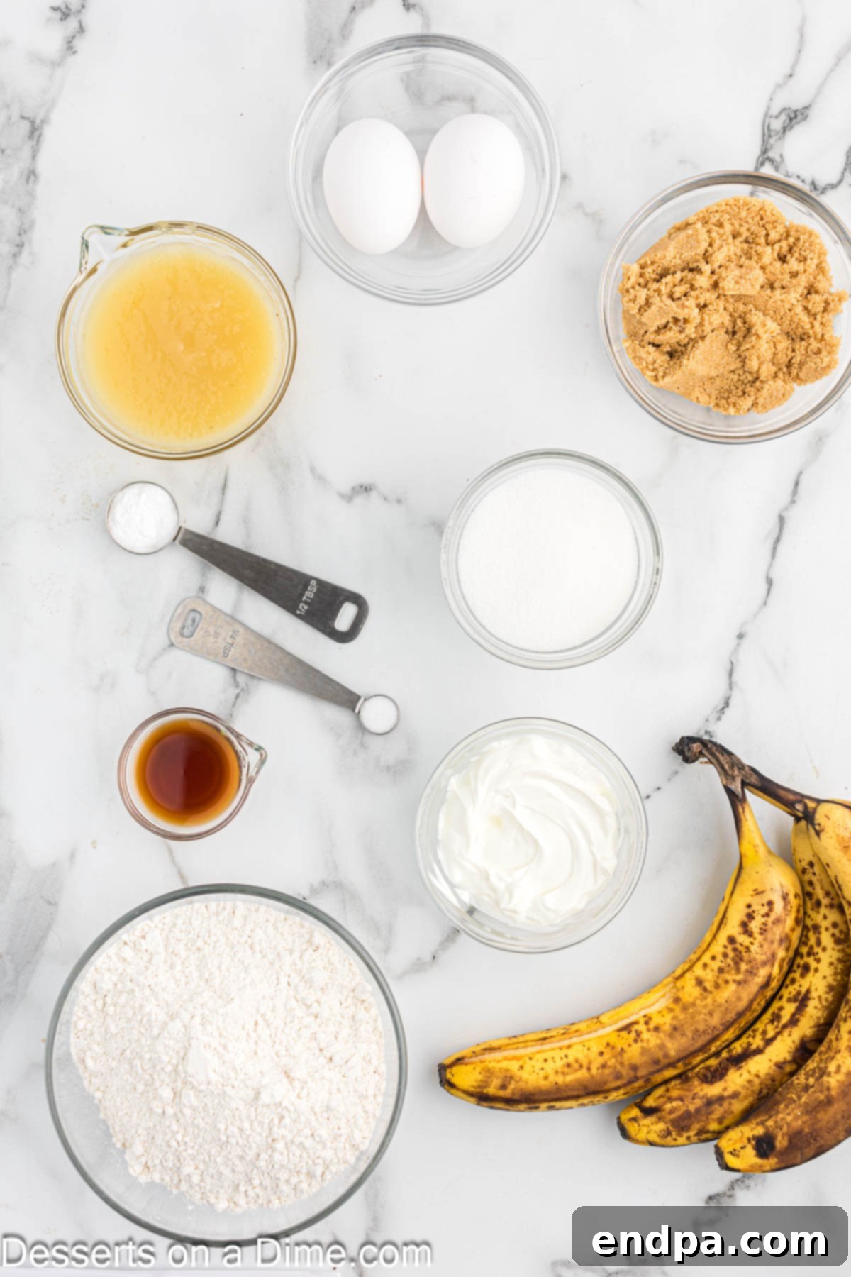 A selection of key ingredients for banana bread including very ripe bananas, a bowl of applesauce, sour cream, sugar, and flour.