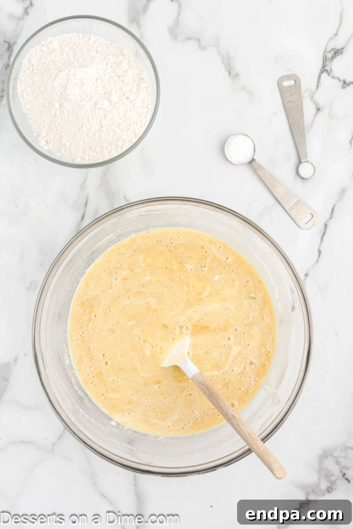 Wet ingredients for banana bread including mashed bananas, applesauce, sour cream, and vanilla extract in a mixing bowl.