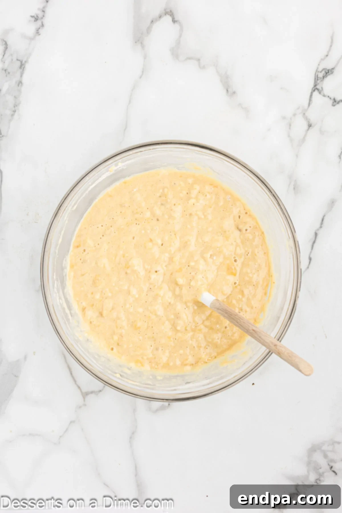 Granulated sugar and brown sugar added to the wet ingredients in a mixing bowl for banana bread.