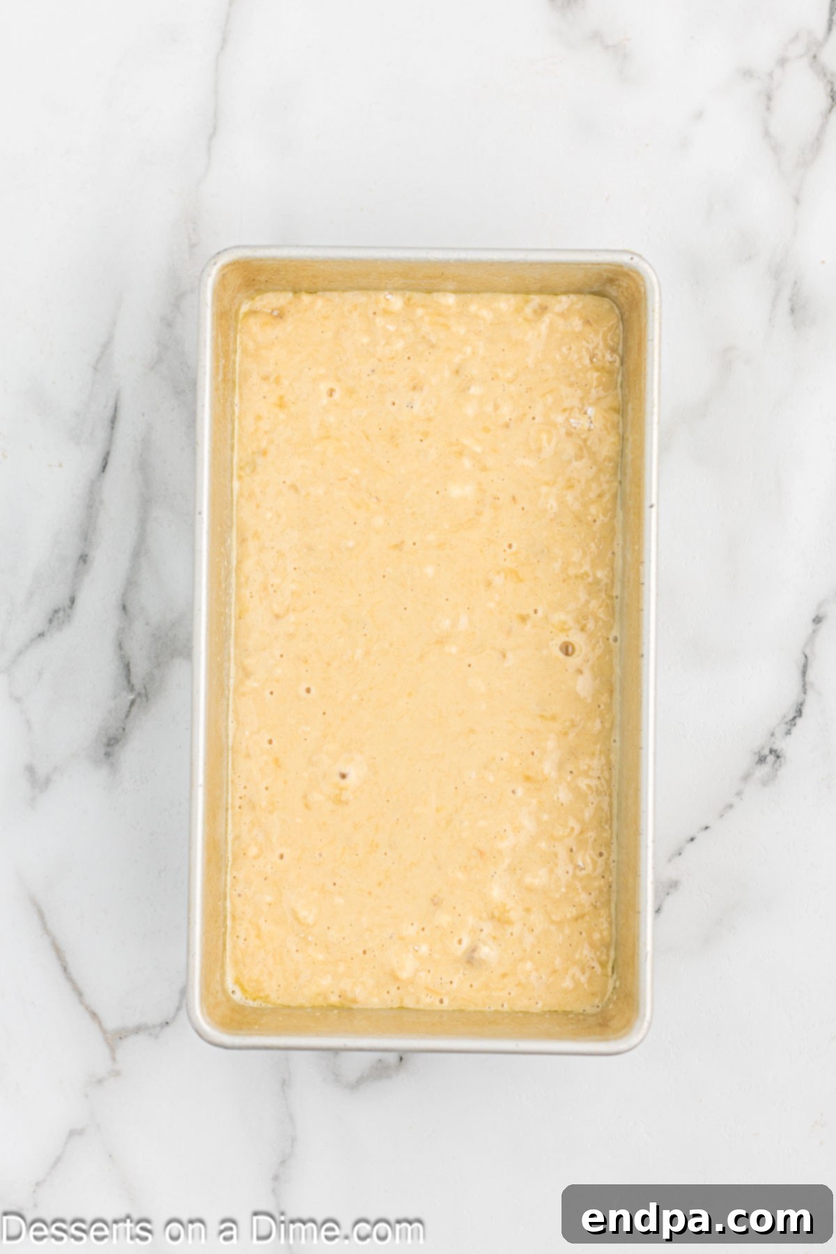Banana bread batter poured into a prepared loaf pan, ready for baking.