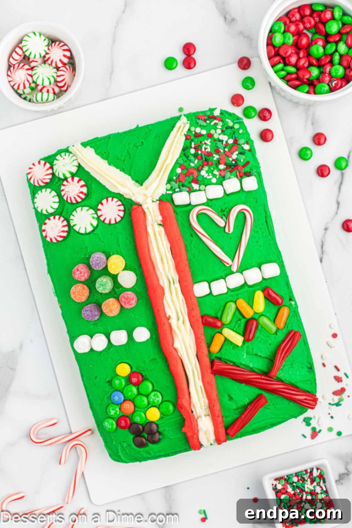 Gaudiest Garment Bake 2 A beautifully decorated Ugly Sweater Cake on a festive platter, showcasing colorful frosting and various candy decorations.