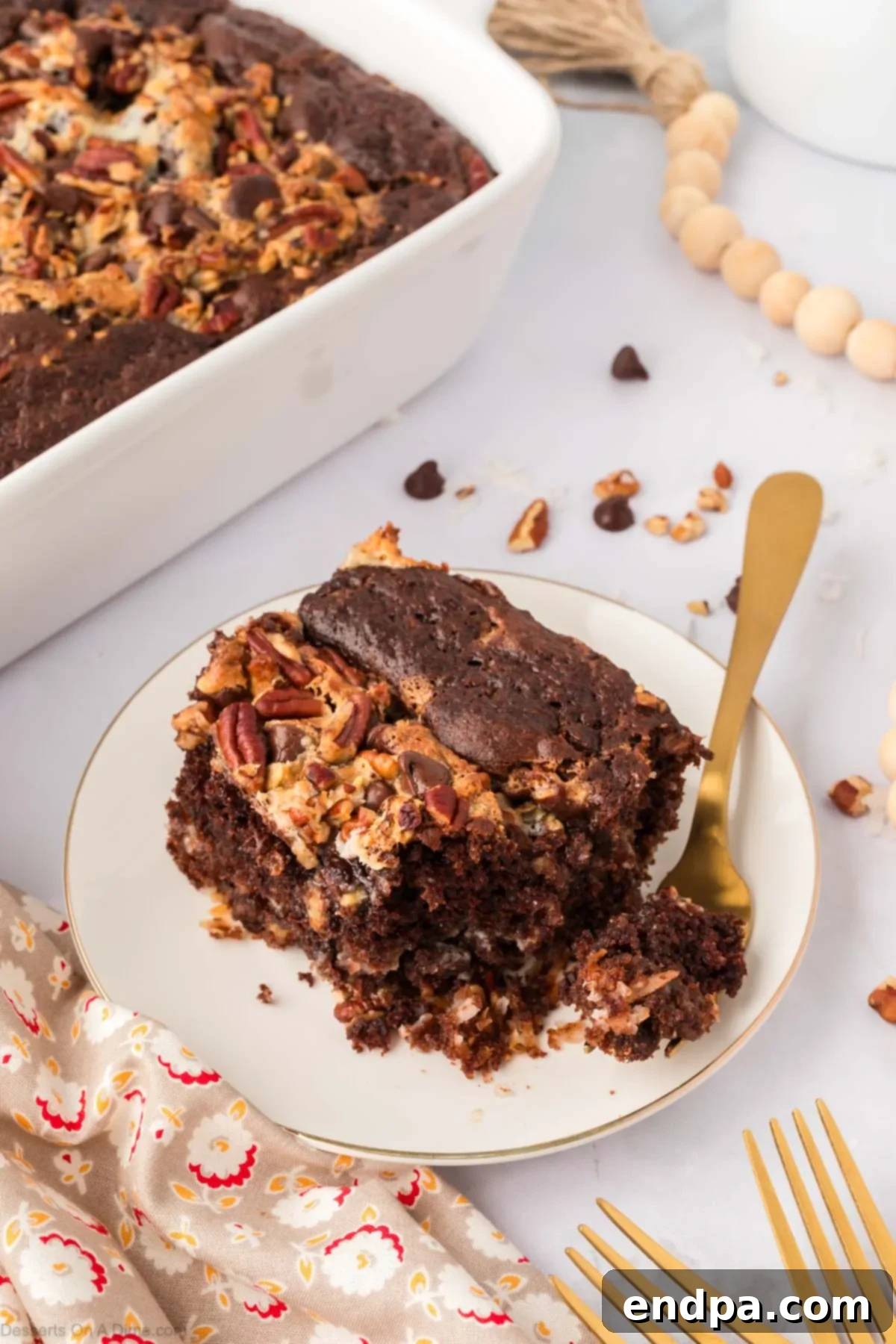 One-Pan German Chocolate Cake 12 Slice of German chocolate dump cake on a white plate, garnished with a sprig of mint.