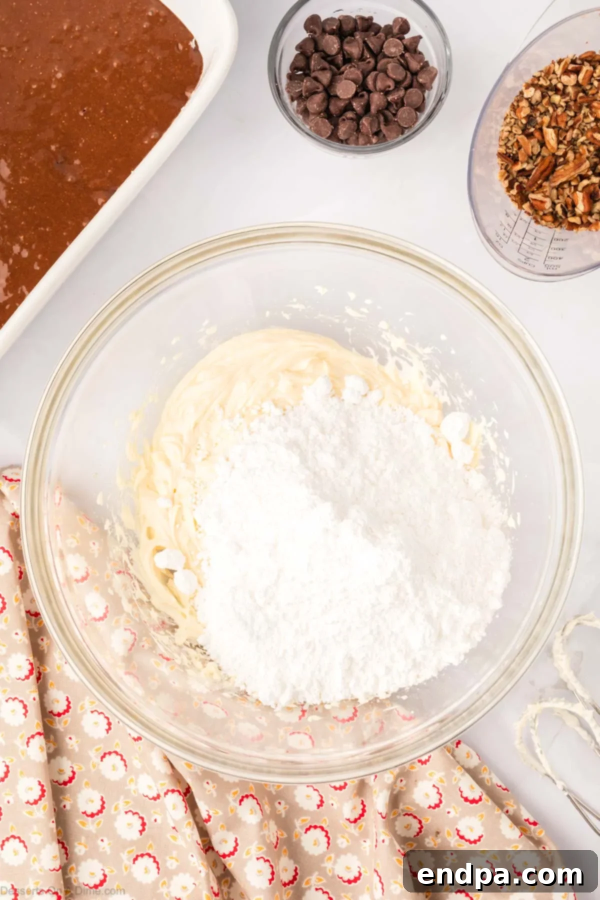 One-Pan German Chocolate Cake 7 Powdered sugar being added to the cream cheese mixture in a bowl and blended.