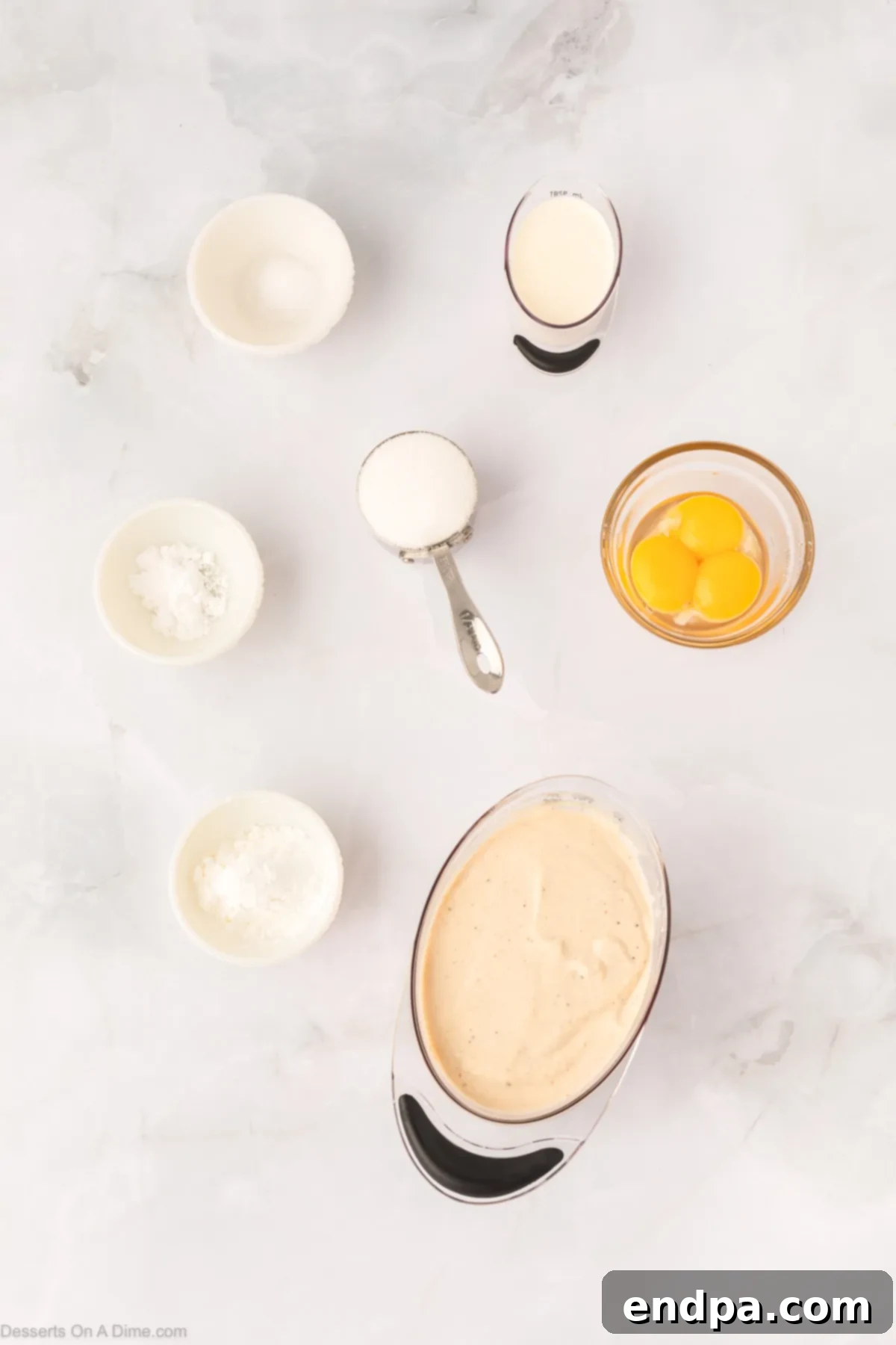 Key ingredients for homemade eggnog pudding including a carton of eggnog, several egg yolks, granulated sugar, confectioners' sugar, and heavy whipping cream, beautifully arranged on a rustic surface.