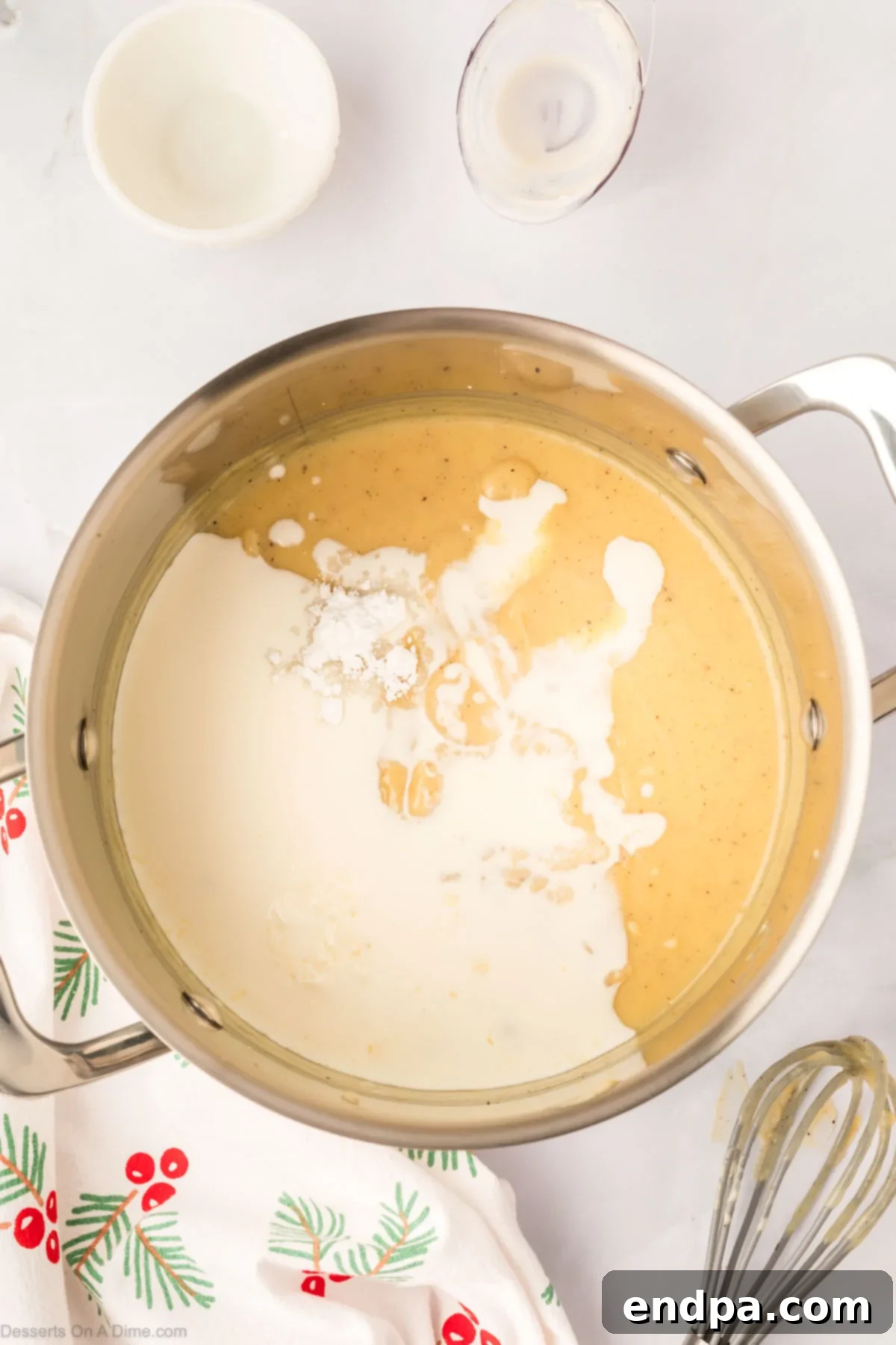 A steady stream of heavy whipping cream being poured into the warm, thickened eggnog pudding mixture in a pot, ready to be stirred for added richness.