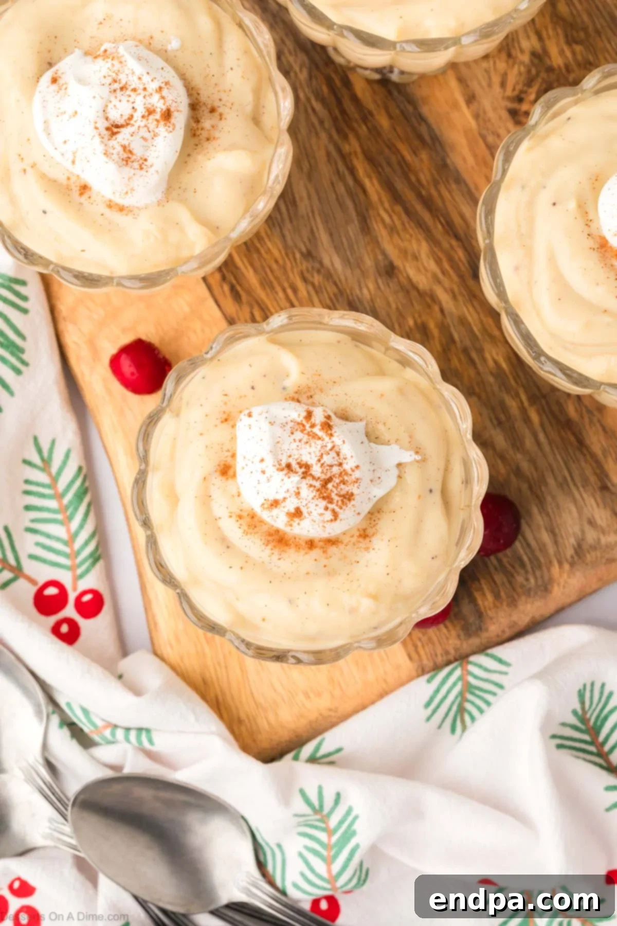 Four small, elegant glasses filled with perfectly chilled and set eggnog pudding, arranged and ready for their final toppings before serving.