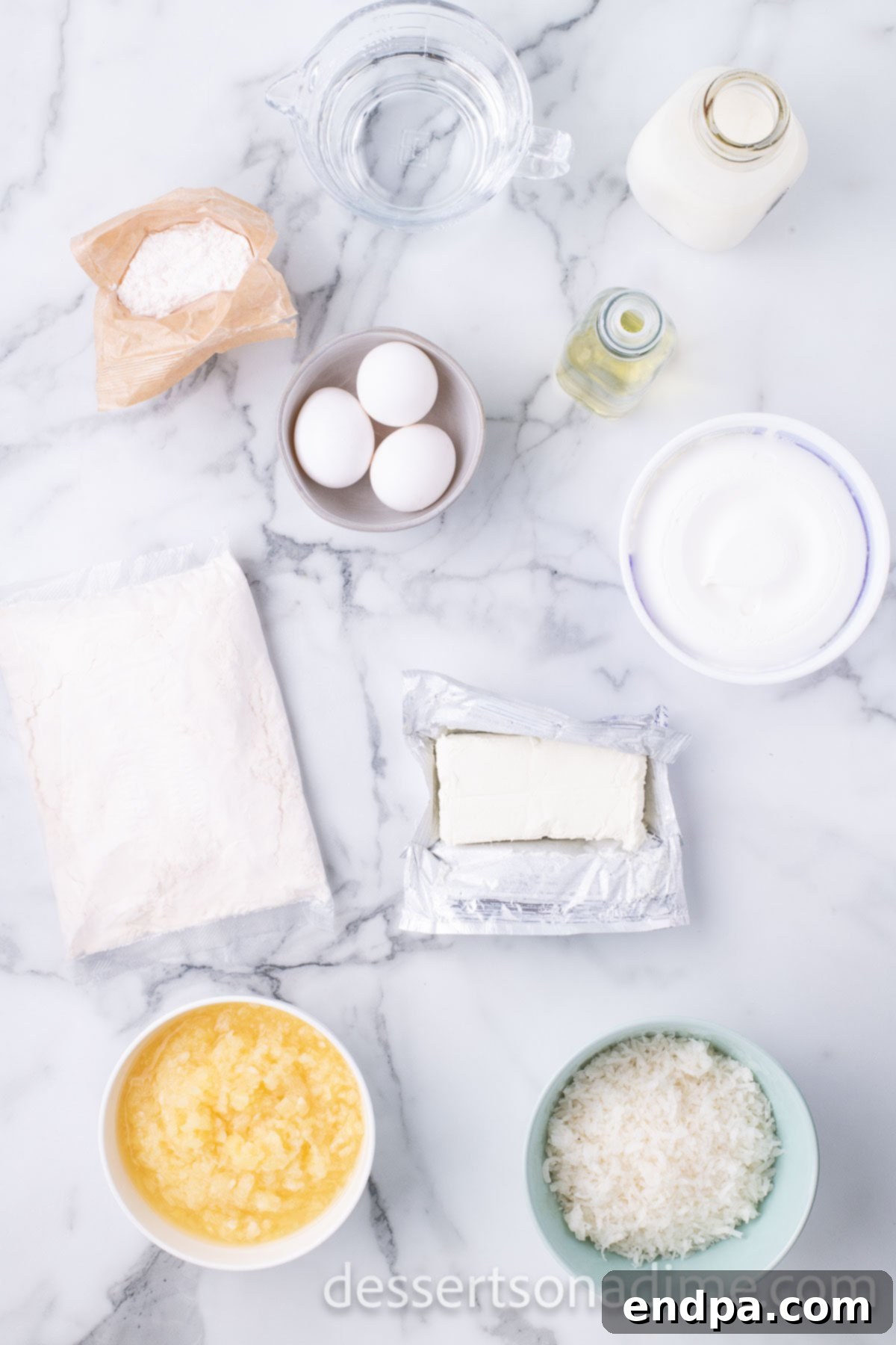All the essential ingredients for Hawaiian Wedding Cake laid out on a clean surface: a box of yellow cake mix, a can of crushed pineapple, a bag of sweetened coconut flakes, a block of cream cheese, a box of instant vanilla pudding, and a tub of whipped topping.