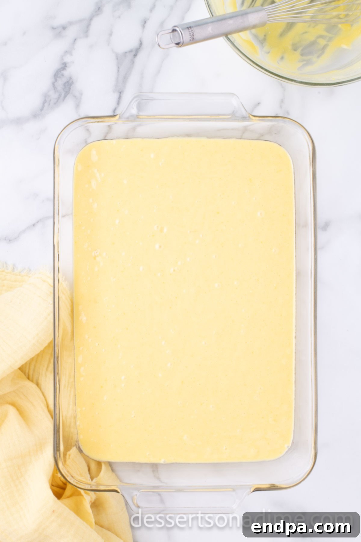 Smooth yellow cake batter poured evenly into a prepared 9x13 inch baking pan, ready to be baked to golden perfection.