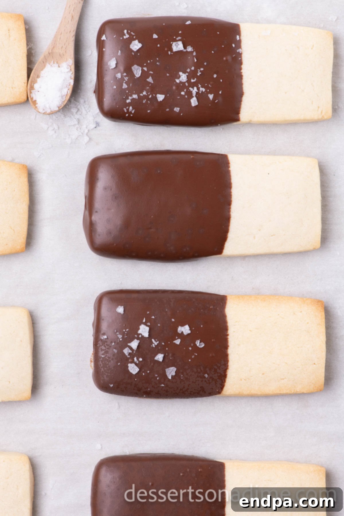 Chocolate-dipped shortbread cookies with sea salt sprinkled on top, waiting to fully set.