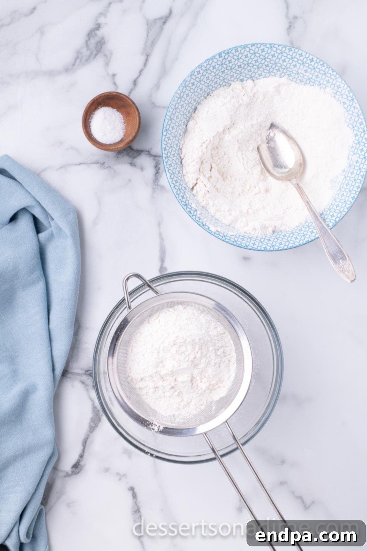 Mixing bowl with flour and sifter, demonstrating the sifting process.