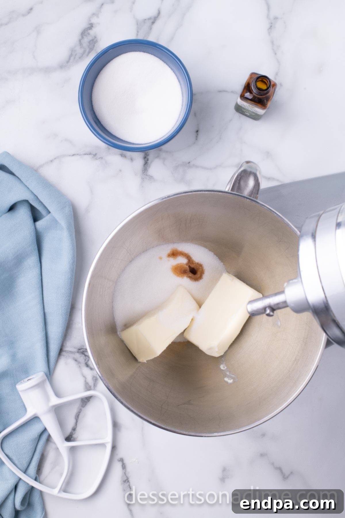Mixing bowl with softened butter, granulated sugar, and vanilla extract being creamed.