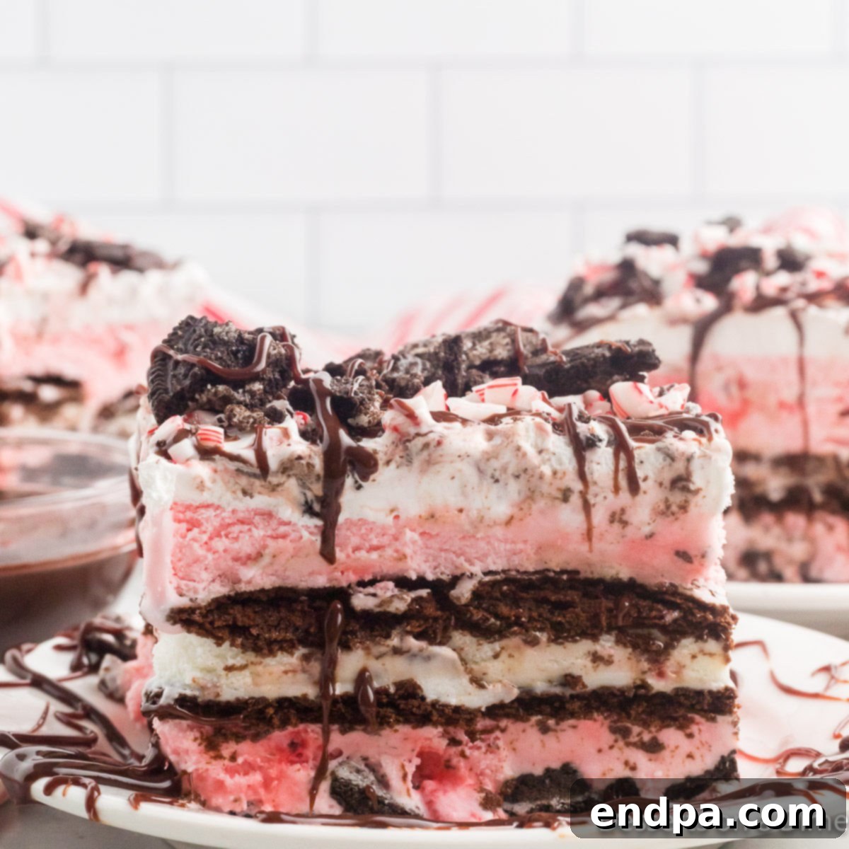 Holly Jolly Ice Cream Cake 13 A slice of Christmas ice cream cake on a plate, showing distinct layers of cookies, ice cream, and toppings.