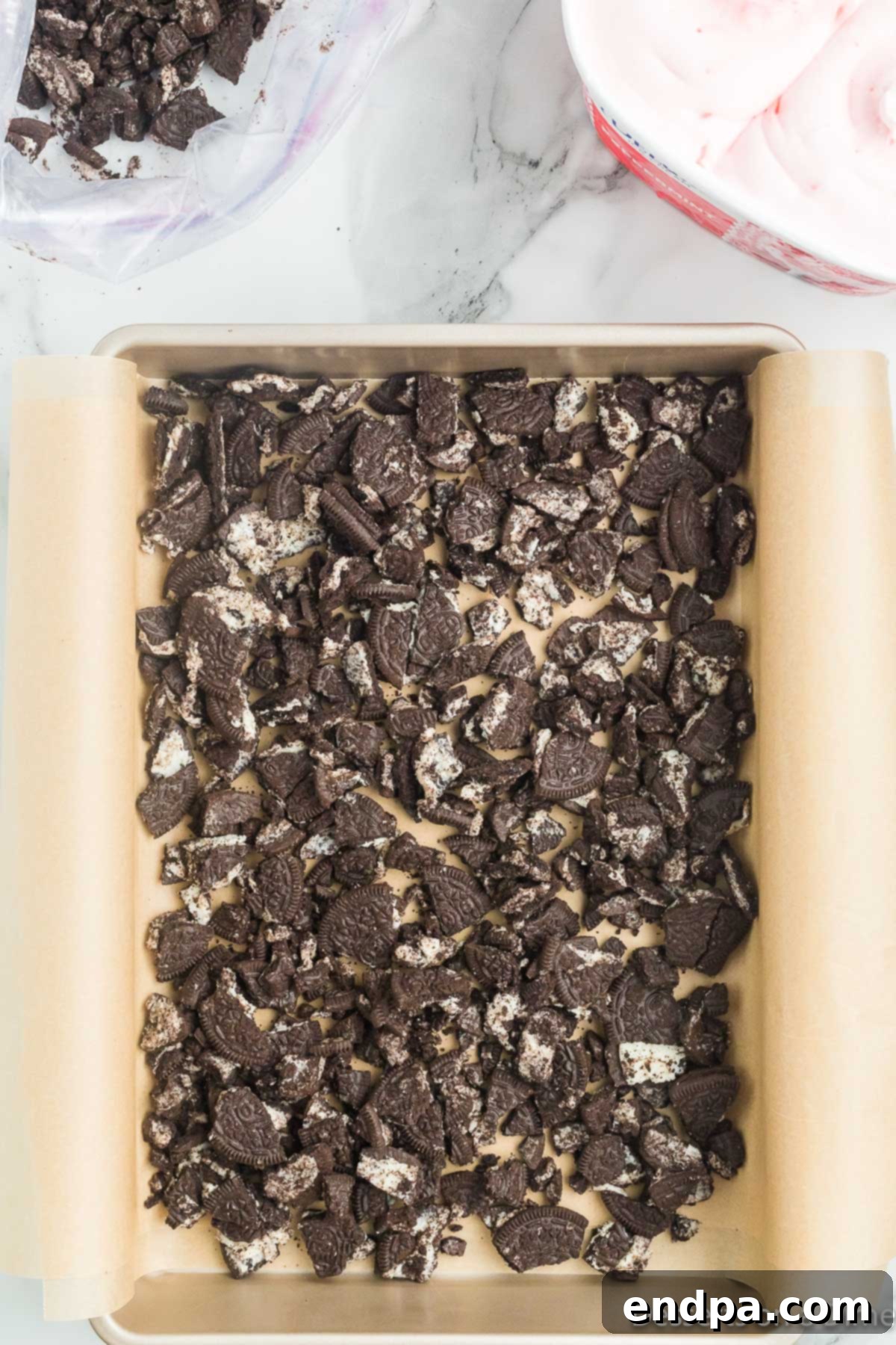 Holly Jolly Ice Cream Cake 6 Crushed Oreo cookies evenly spread at the bottom of a baking pan.