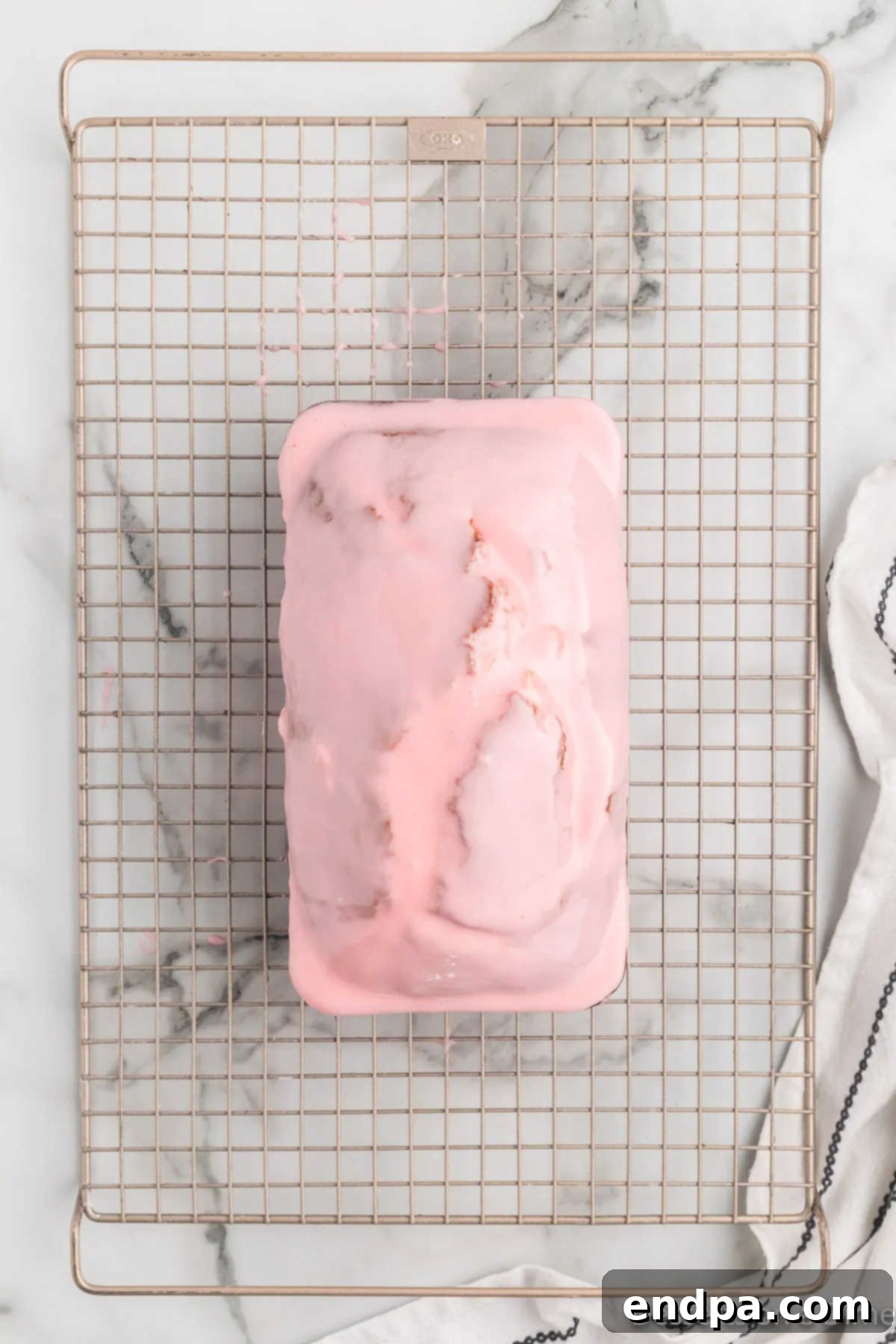 Glazed loaf of Cherry Bread resting on a cooling rack, allowing the glaze to set.