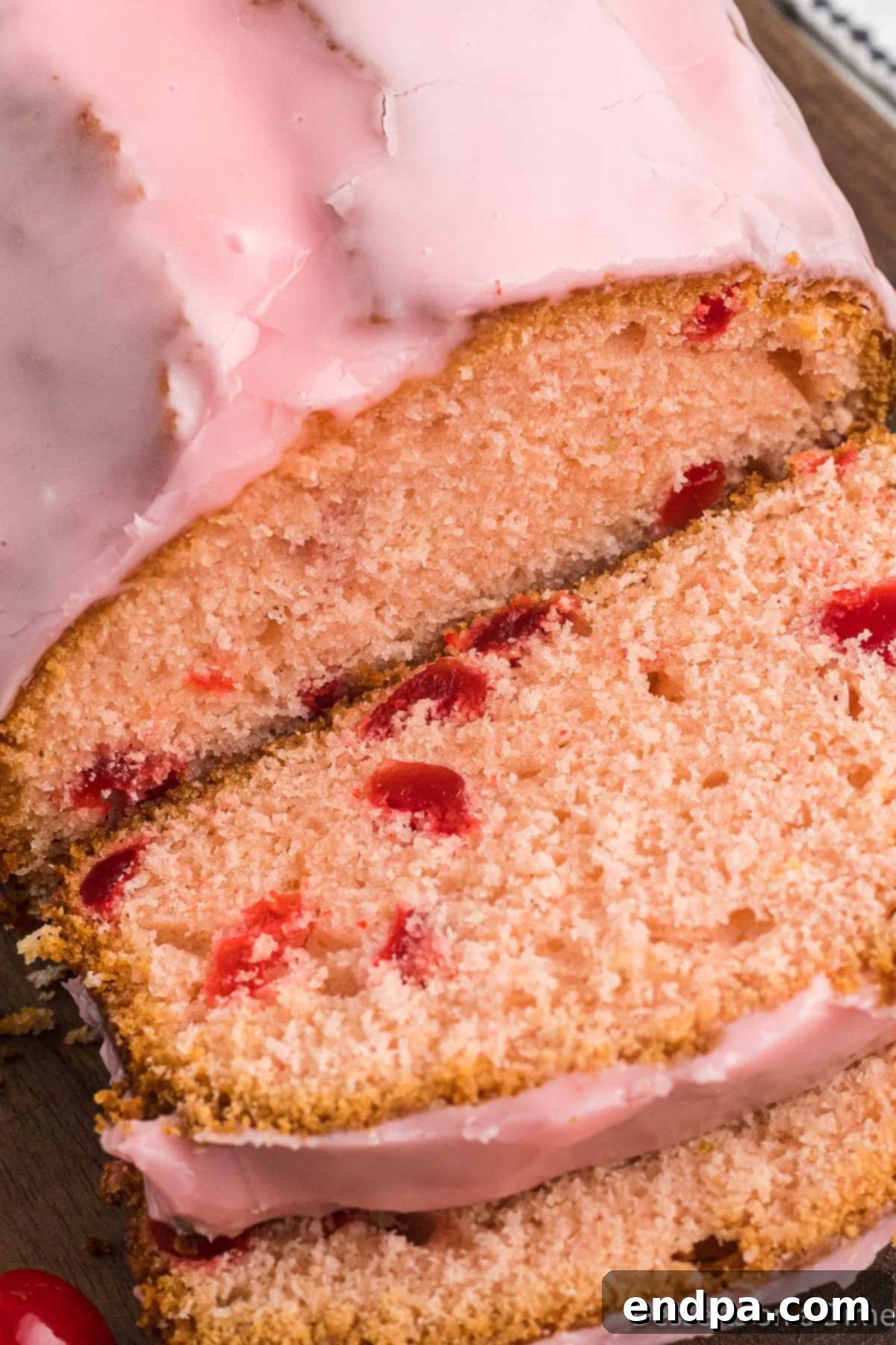 Close-up of a sliced loaf of cherry bread, showing the moist crumb and evenly distributed cherries.