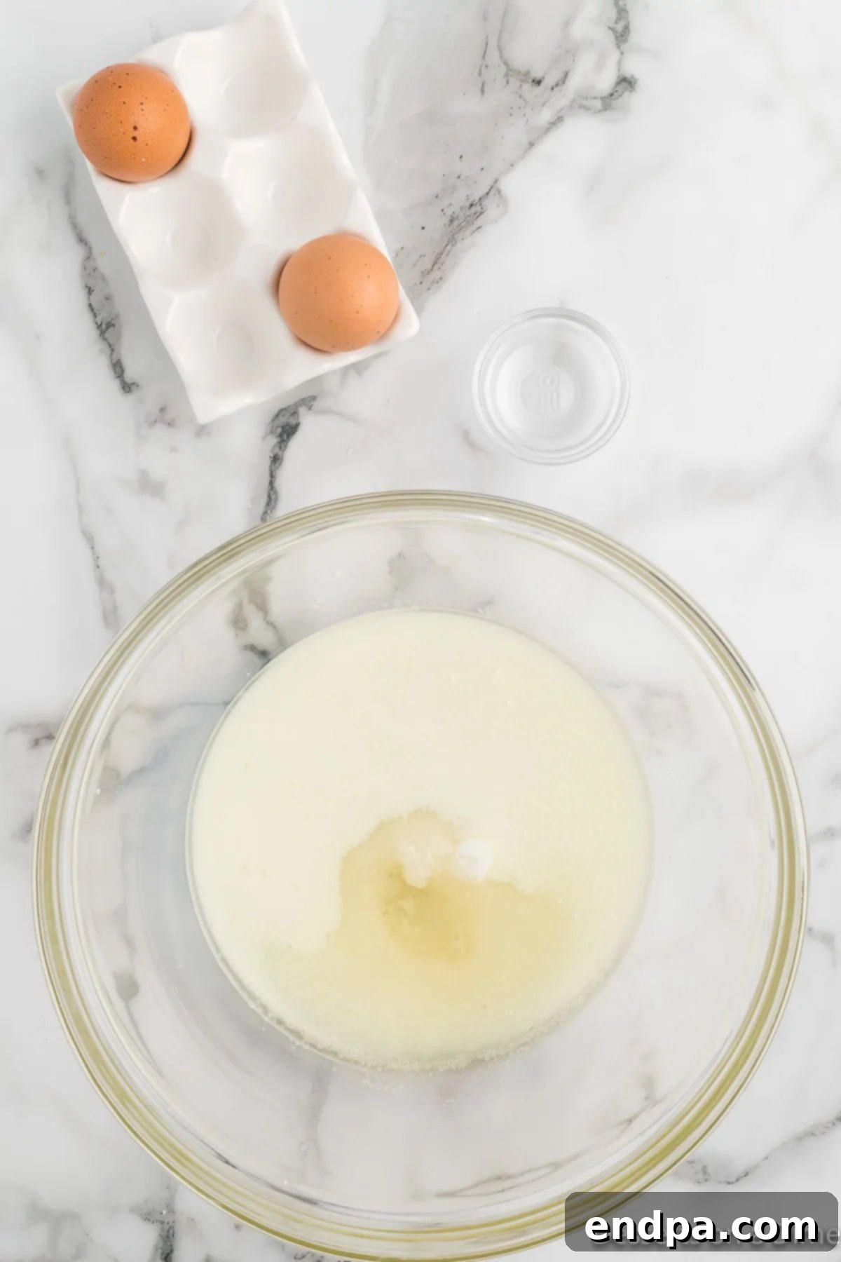 A separate mixing bowl with milk, vegetable oil, eggs, and almond extract.