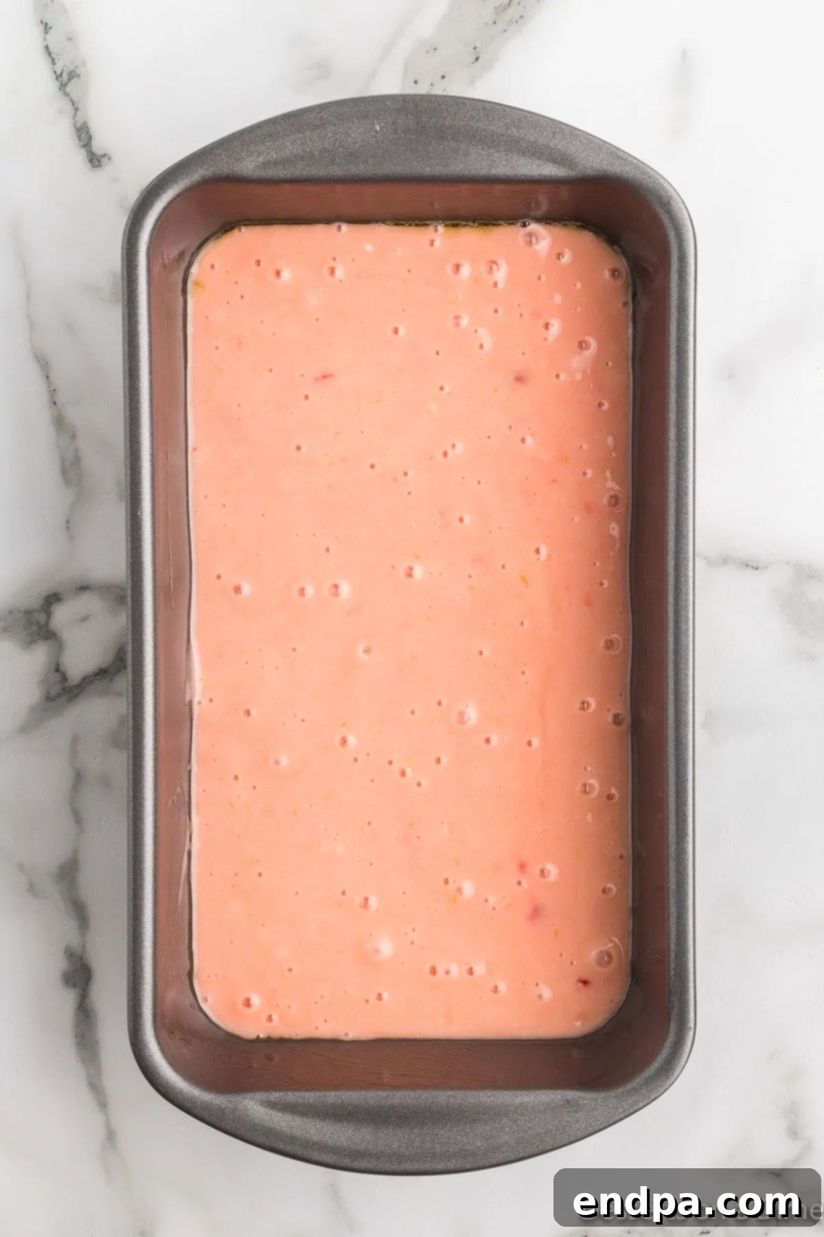 Loaf pan filled with cherry bread batter, ready for baking.