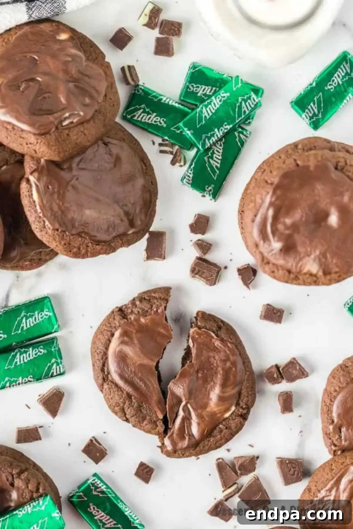 Delicious chocolate Andes Mint Cookies, freshly baked and ready to be enjoyed. Each cookie is topped with a melted Andes Mint, creating a smooth, glossy finish that marries the rich chocolate cookie with a cool mint flavor.