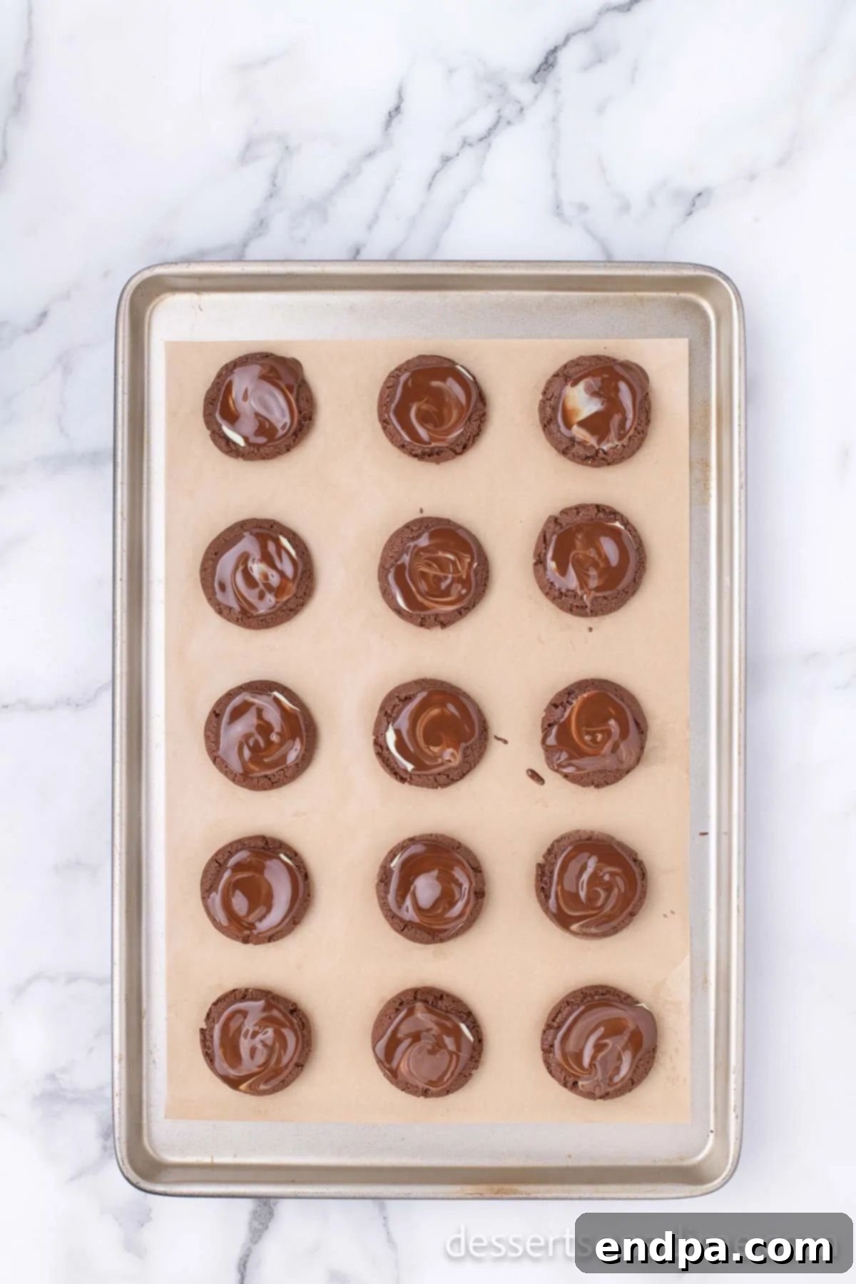 Warm chocolate cookies, fresh from the oven, with an unwrapped Andes Mint placed on the center of each, gently melting from the residual heat.