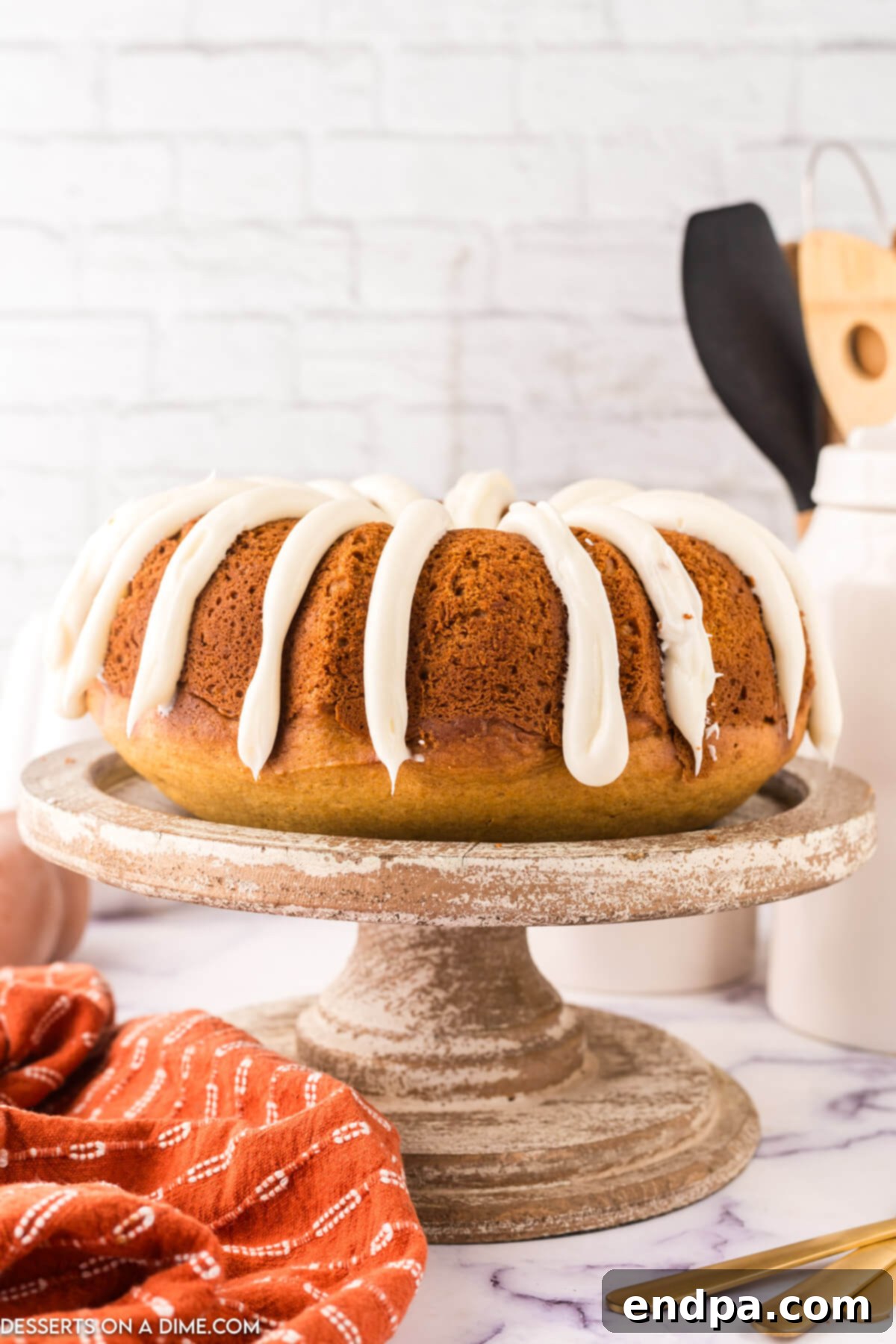 Pumkin Bundt Cake on a platter, drizzled with cream cheese frosting.