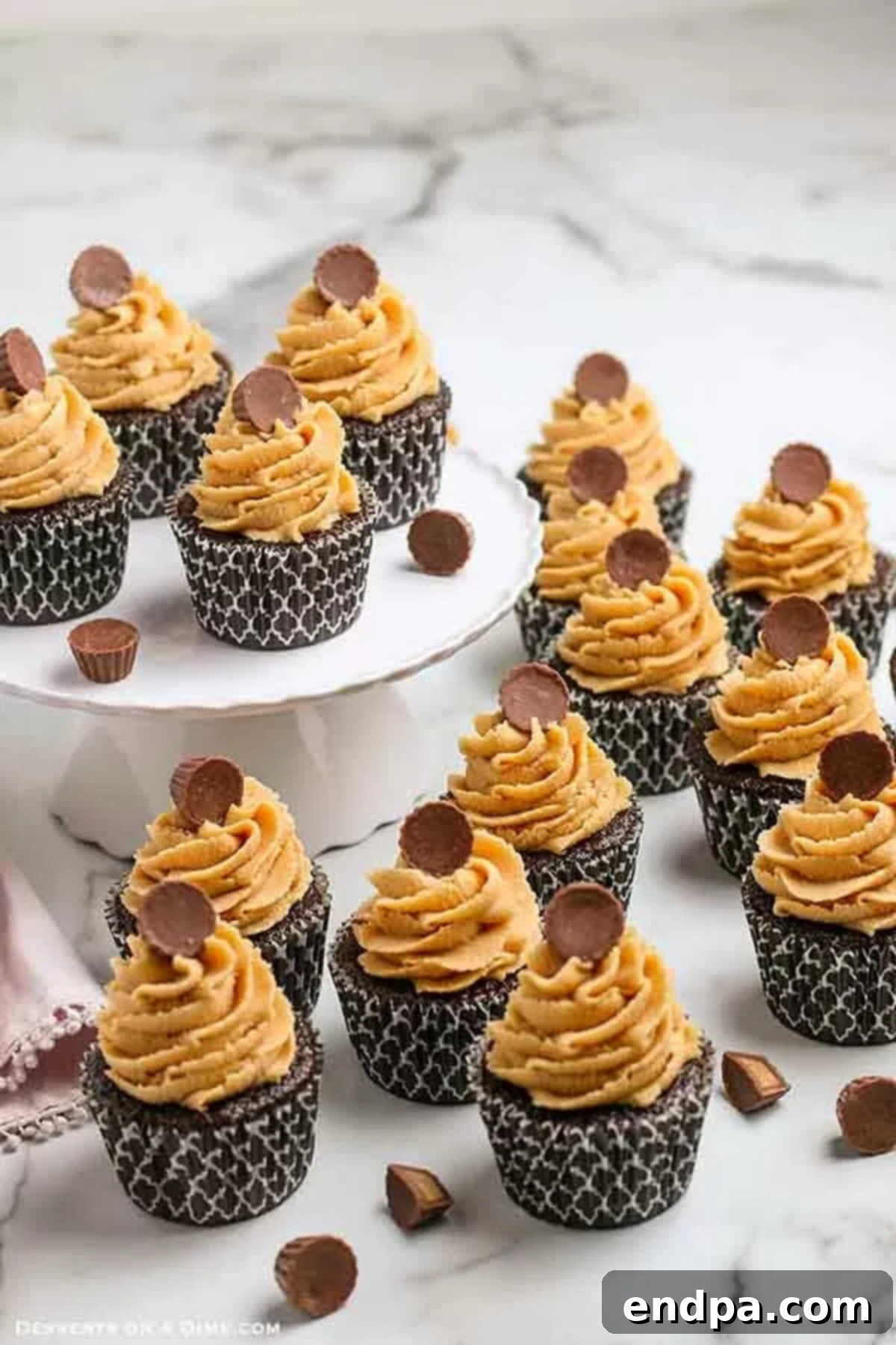 Close-up of perfectly frosted Chocolate Peanut Butter Cupcakes, each topped with a Reese's Peanut Butter Cup, ready to be enjoyed.