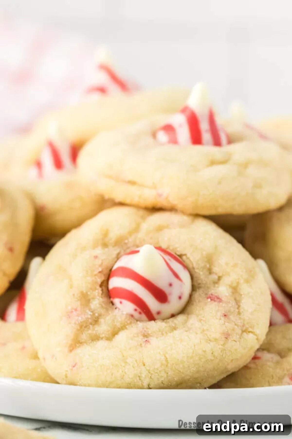 Stacked Candy Cane Kiss Cookies on a festive platter, showcasing their vibrant red and white Hershey's Kiss tops and soft texture, ready for Christmas celebrations.