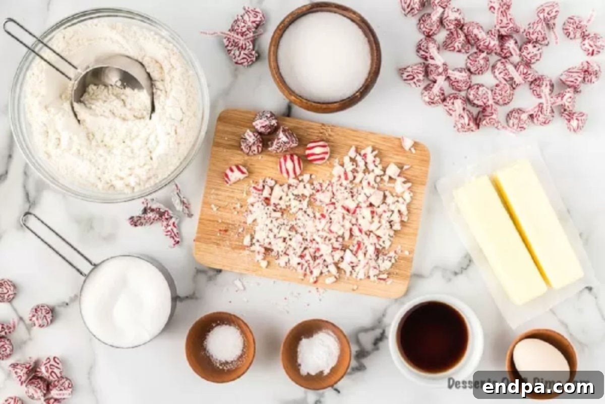 A flat lay photograph displaying all the ingredients needed to make Candy Cane Kiss Cookies: softened butter, granulated sugar, Hershey's Candy Cane Kisses, vanilla extract, an egg, all-purpose flour, baking soda, and salt.