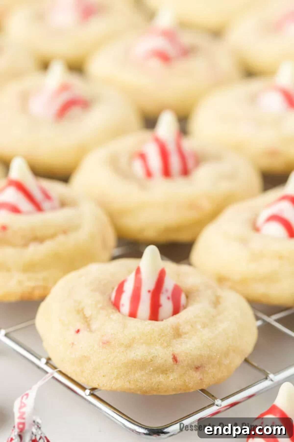 Freshly baked Candy Cane Kiss Cookies cooling on a wire rack, showcasing their perfect round shape and the set Hershey's Kiss on top, ready to be enjoyed.