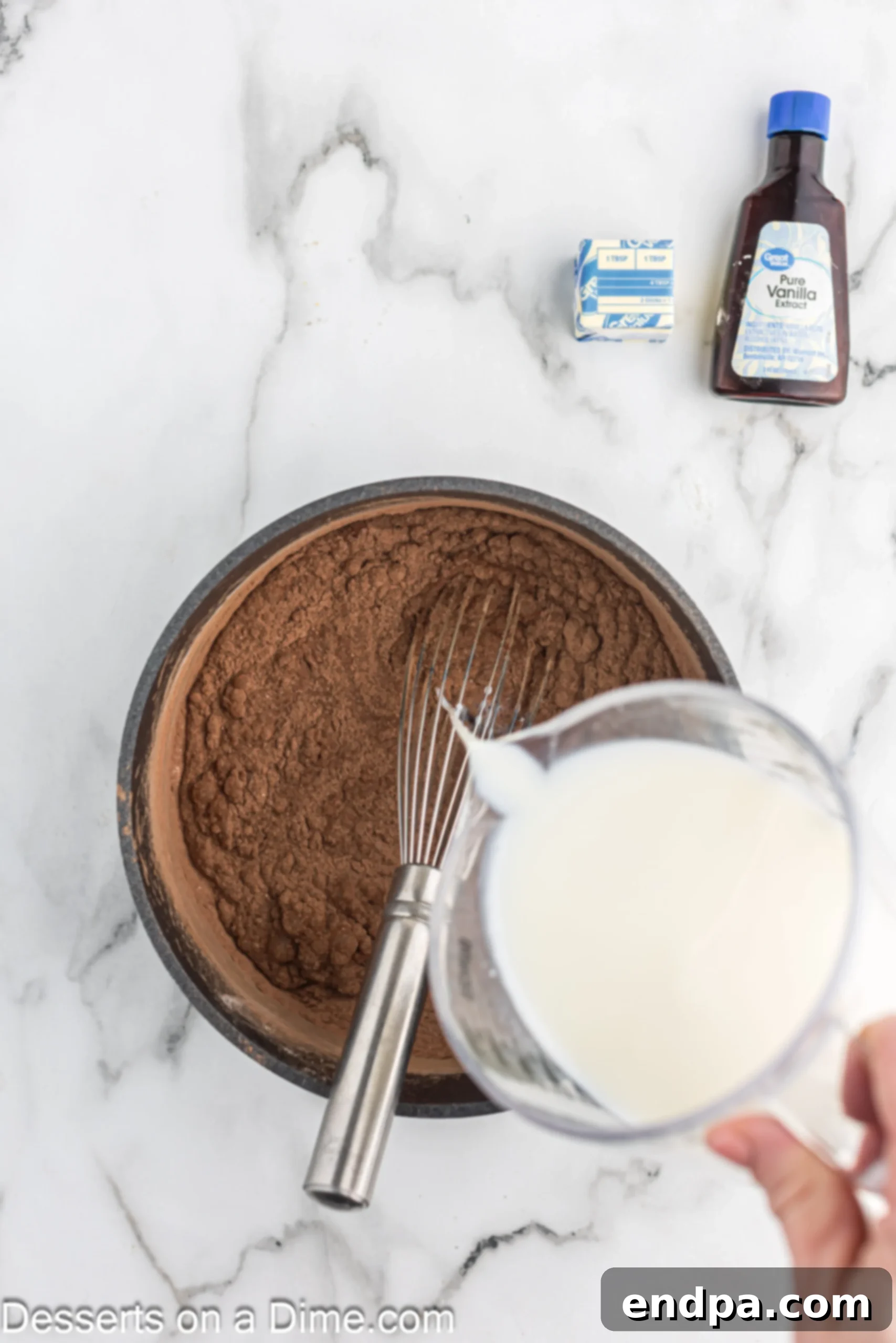 Decadent Chocolate Dream 5 Milk being added to a saucepan with dry ingredients for chocolate pudding, prior to whisking and heating.