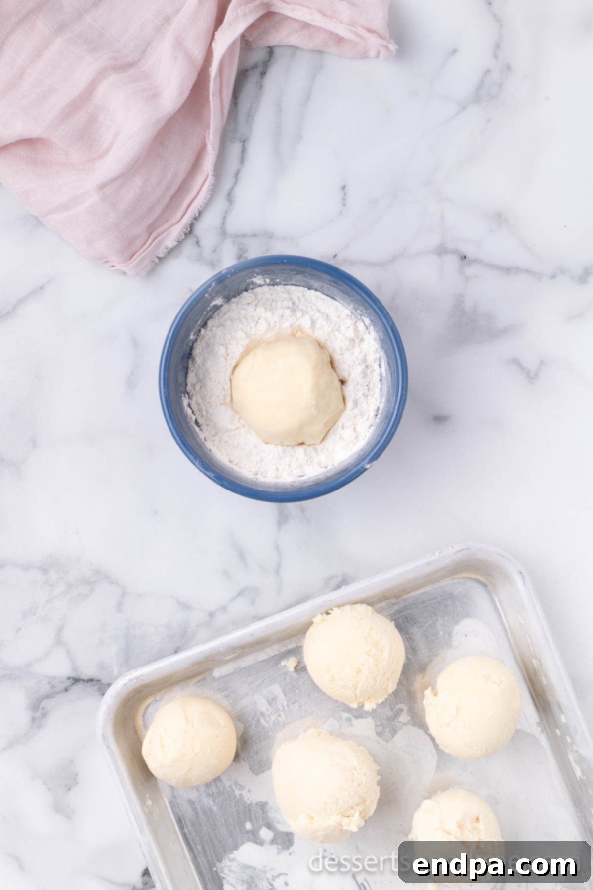 Ice cream balls rolled in flour and returned to a baking sheet for freezing.