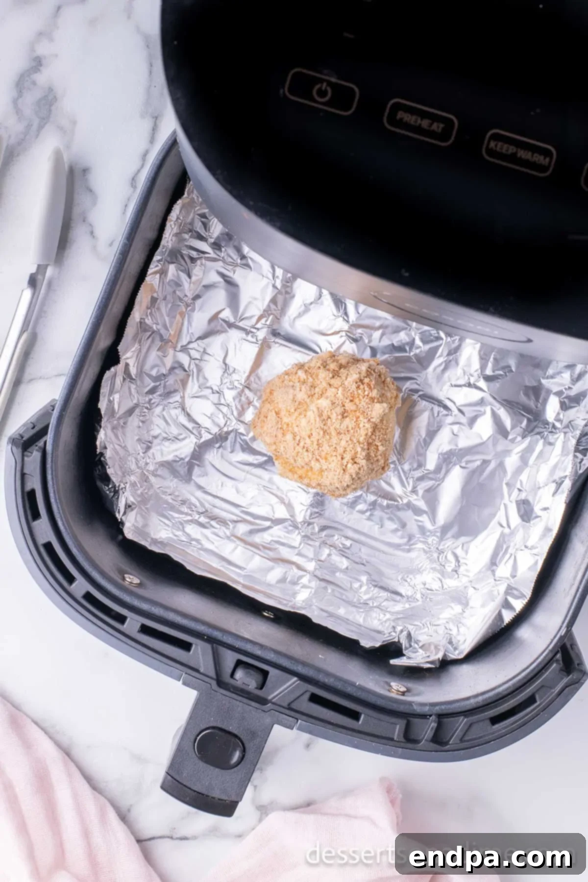 Coated ice cream balls placed in an air fryer basket, ready for cooking.