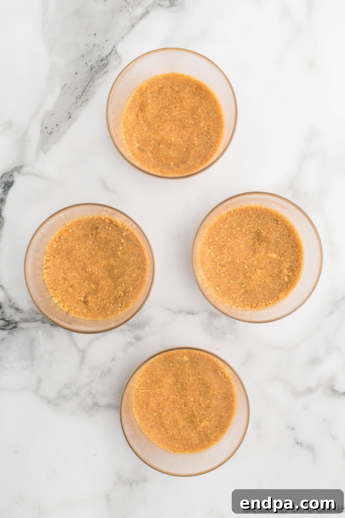 4 bowls with graham cracker crust in the bottom.