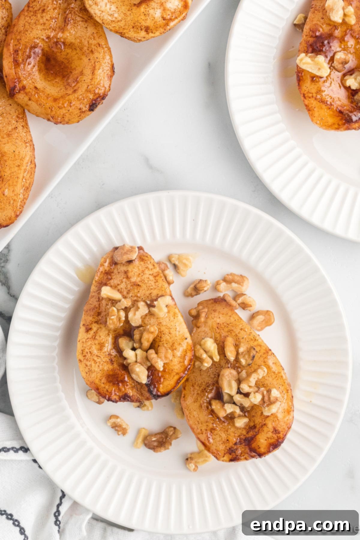 Golden brown Air Fryer Pears on a plate, garnished with walnuts and a drizzle of honey.