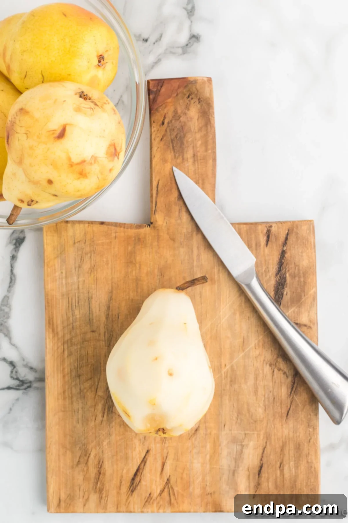 A ripe pear on a cutting board, ready for peeling.