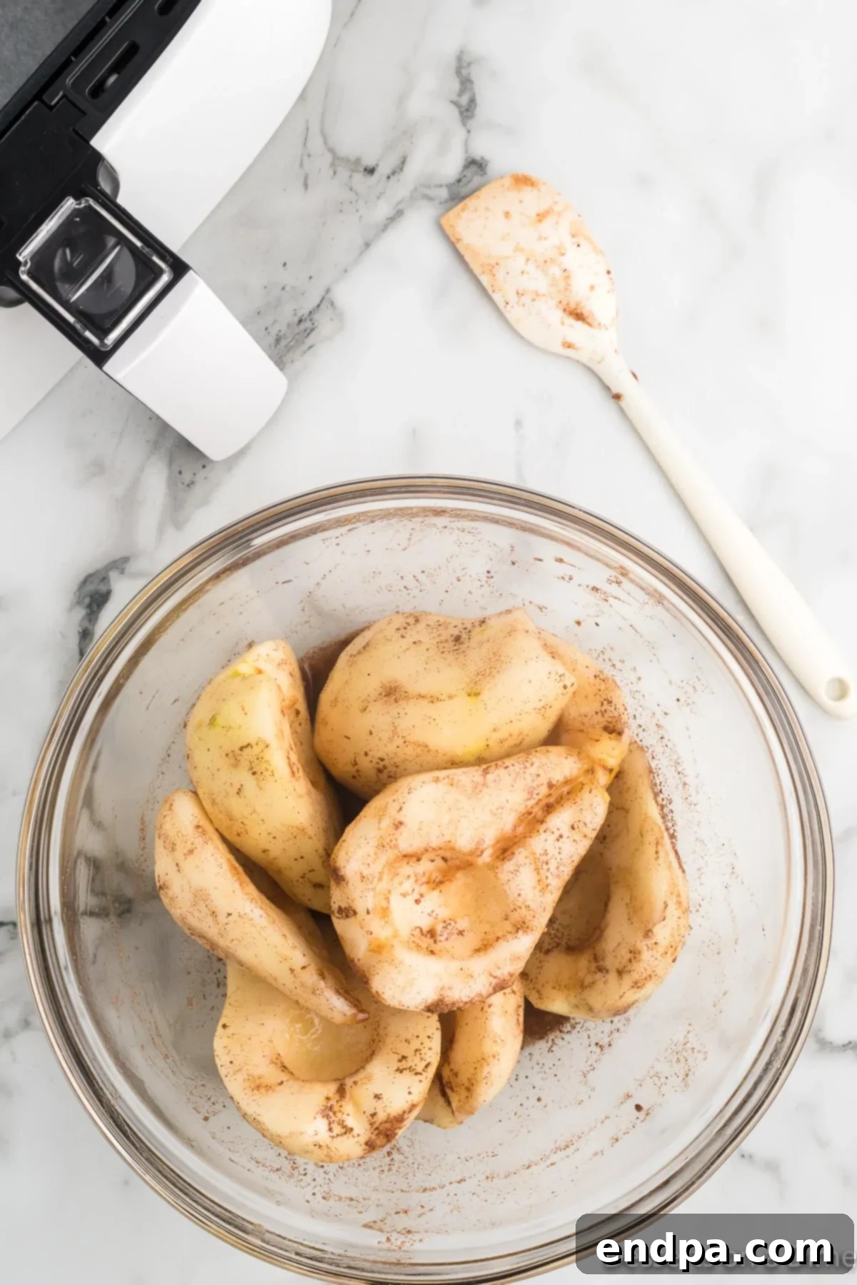 Pear halves in a bowl, being drizzled with the maple syrup mixture.