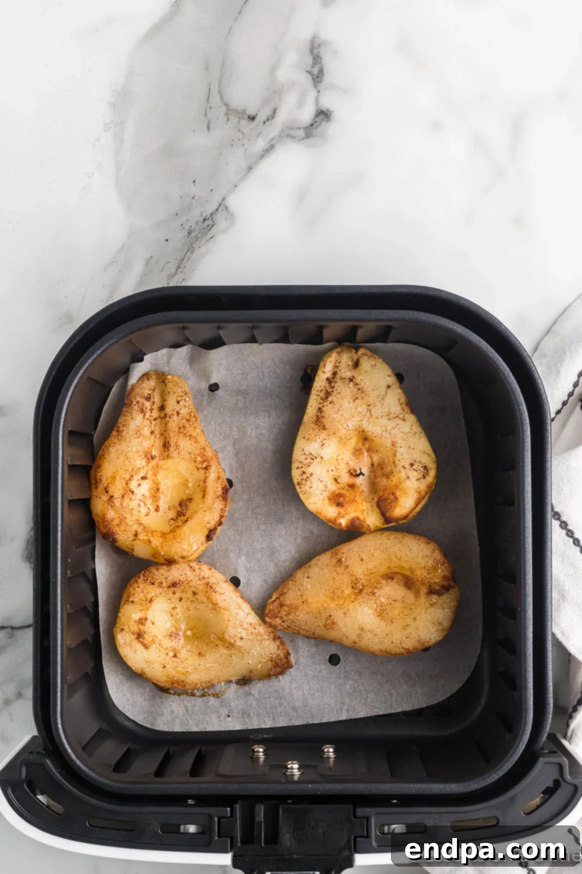 Cooked air fryer pears, golden brown and caramelized, still in the air fryer basket.