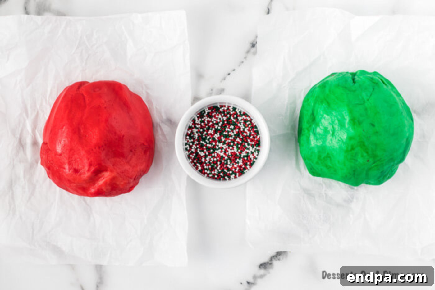 Red and green colored cookie dough in separate bowls