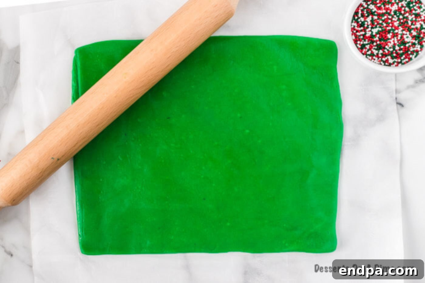 Red cookie dough rolled out on parchment paper