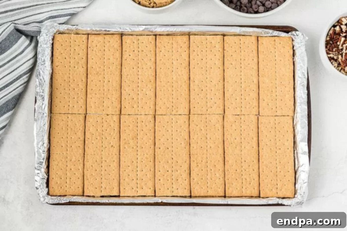 Graham cracker sheets neatly arranged in a single layer on a prepared jelly roll pan.